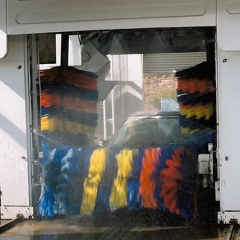 Vehicle wash with colourful red and yellow brushes in action